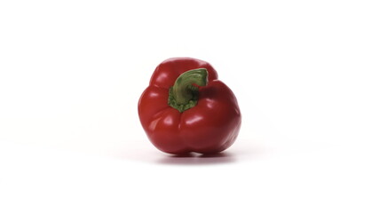 One fresh red pepper is spinning on white background. Freshly picked vegetable on turntable rotate. Detail view isolated.