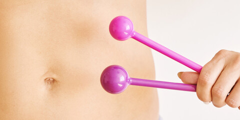 Young woman hand holding femine sex toys. Kegel adult exercise. Intimate gymnastics. Recovery vagina pain. Light background. Gynecology health ball. Health stomach. Horizontal banner