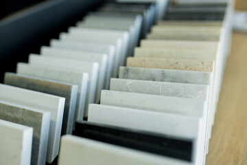 Close-up sample of stone for new kitchen countertop in showroom. Various types of marble, quartz, granite for home renovation. Selective focus