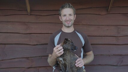 A young man petting his mongrel dog in the village.