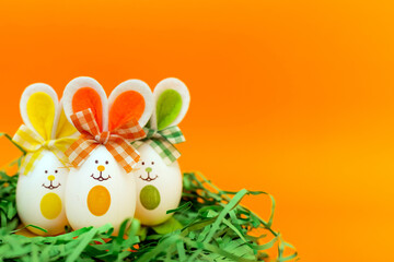 Fototapeta na wymiar Three Easter eggs with bunny ears on nest spring yellow background.