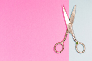 Pair of Old Used Metal Rusty Scissors Placed Over Pink And Blue Paper Background.