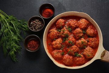 Boulettes de Poisson, Fried Fish Balls in Tomato Sauce in a white dish on a concrete table with ingredients