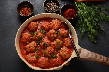 Boulettes de Poisson, Fried Fish Balls in Tomato Sauce in a white dish on a concrete table with ingredients