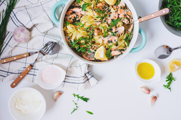 italian cuisine - creamy salmon pasta with arugula, spinach and cheese served with lemon