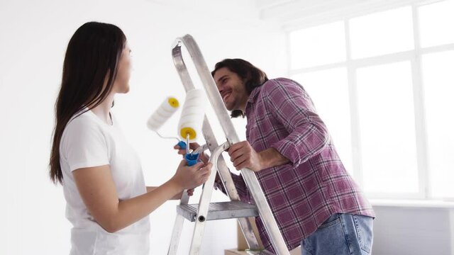 Young happy married couple dancing and fooling around with work tools, making repair at her apartment