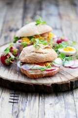 sanduíche de pão rústico - queijo macio, salame, ovo cozido, rabanete, ervas. 