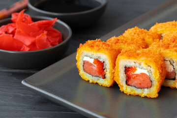 Sushi roll fried in tempura on black plate