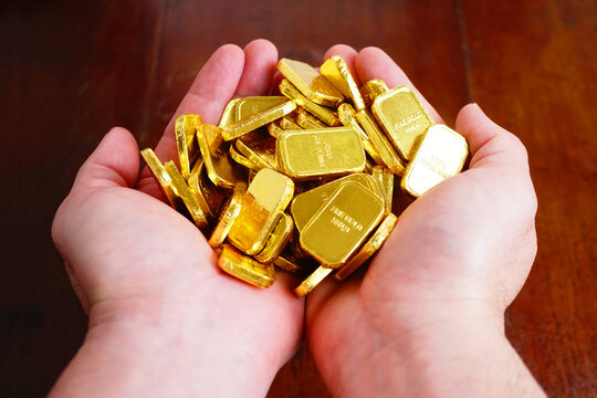 Two hands hold group of gold bars.