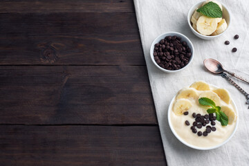 Healthy breakfast, dessert with milk yogurt banana and chocolate on a plate. Dark wooden background. Top view, copy space.