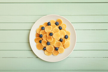 Plate of tasty pancakes with  fresh blueberry on color wooden background