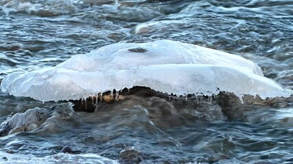 Stone with ice on the top laying in a fast flowing river - Powered by Adobe