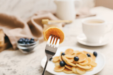 Fork with tasty pancake and fresh blueberry on blurred background, closeup