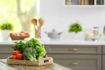 Tray with vegetables on table in modern kitchen