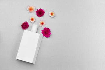 Perfume spray bottle and little flowers on gray background
