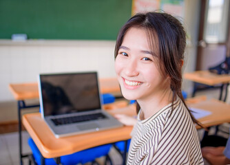 happy asian Student girl  using  laptop in classroom