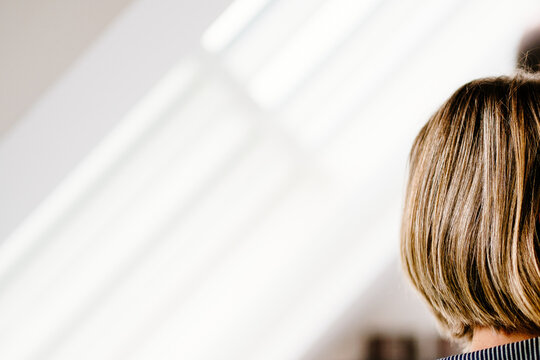 back side headshot of brown haired woman in front of diagonal light