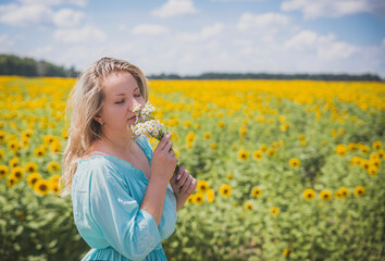 Attractive blonde in a blue dress in a field of sunflowers
