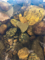 The heart-shaped stone lies at the bottom of the river, vertical orientation