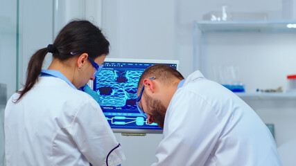 Obraz premium Team of scientists discussing about virus development in front of pc in modern equipped laboratory. Multiethnic stuff analysing vaccine evolution using high tech for researching treatment