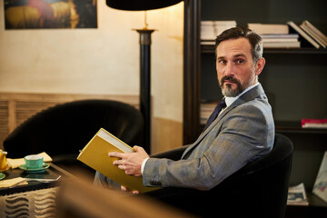Bearded gentleman looking interested while lounging in armchair