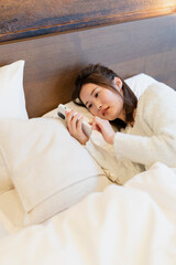 寝室でスマートフォンを使う女性