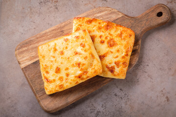Two slices of khachapuri with cheese on a wooden cutting board. National Georgian dish.