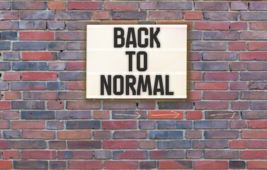 Obraz premium Back To Nomal text in lightbox on brick wall