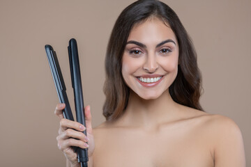 Young woman with bare shoulders with flat iron