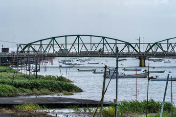 View of river and steel truss bridge in countryside, Japan.
