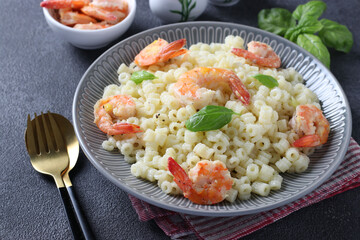 Italian ditalini pasta with shrimps and basil in gray plate on a dark background. Closeup.