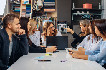 Successful hardworking and beautiful team of workers discussing the project at one white table. Smiling girl came up with an idea and she happily telling it to her boss. Joyful boss likes this idea. 