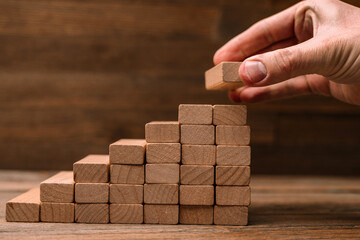 Business concept - hand builds a ladder from wooden blocks. Driving business at the peak concept.