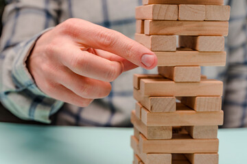 Business man in a shirt builds a tower of wooden blocks as a symbol of development and planning in business, a strategy for success
