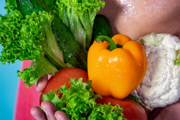 Slim male body and fresh vegetables. Healthy food and sports. Diet and weight loss. Blue background.