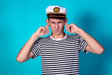 Funny experienced sailor ready for marine travel. Cheerful young sailor. Expression of emotions. The guy is posing on a blue background.
