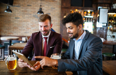 Meeting with the best friends. Happy young business men talking and drinking beer in a pub