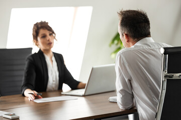 Business meeting. Two business people sitting at office desk discussing work.