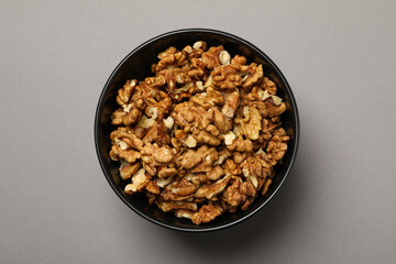Obraz na płótnie Canvas Bowl with tasty walnuts on gray background