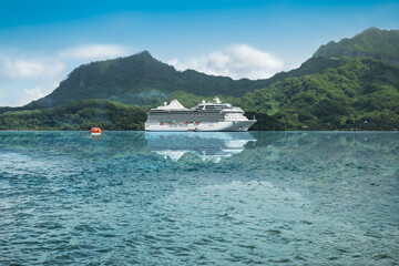 Fototapeta na wymiar Luxurious cruise ship reflecting in the waters of a beautiful bay of the Leeward Islands in French Polynesia.
