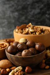 Bowl with macadamia and different nuts on wooden table