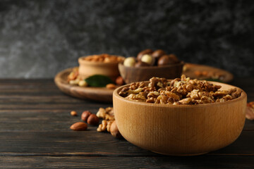 Wooden bowl with walnuts on wood background, space for text