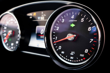 Fototapeta premium Close up shot of a tachometer in a car. Car dashboard. Dashboard details with indication lamps. Car instrument panel. Dashboard with speedometer, tachometer, odometer. Car inside