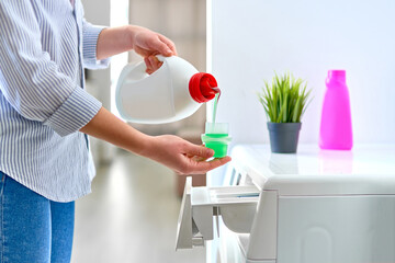 Woman housewife using fabric softener detergent gel for washing machine at laundry day