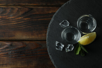 Tray with shots of vodka on wooden background