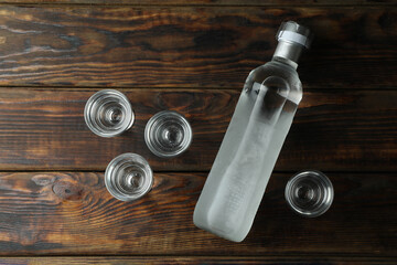 Obraz na płótnie Canvas Blank bottle of vodka and shots on wooden background