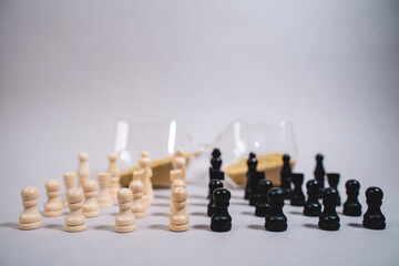 black and white chess pieces standing against the background of the hourglass