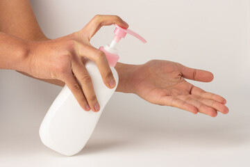 The hand was holding the pump bottle and pressing the lotion onto the palm.