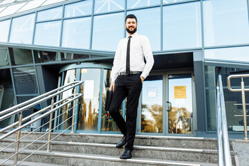 young bearded businessman in business clothes near office building in the city