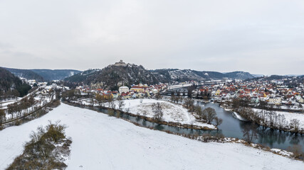 Luftaufnahme einer Drohne der Stadtansicht des Markt Kallmünz Kallmuenz in Bayern und Brücke über Fluss Naab und Burg Ruine im Winter mit Schnee und Eis, Deutschland